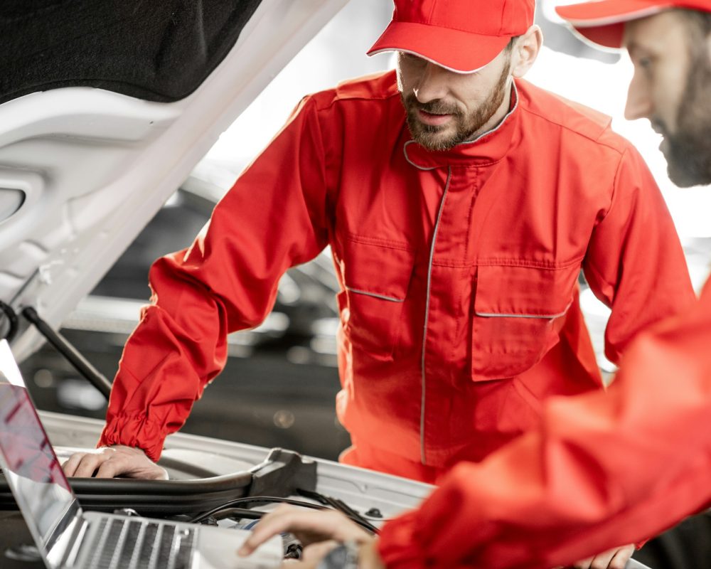 Auto mechanics doing diagnostics with laptop